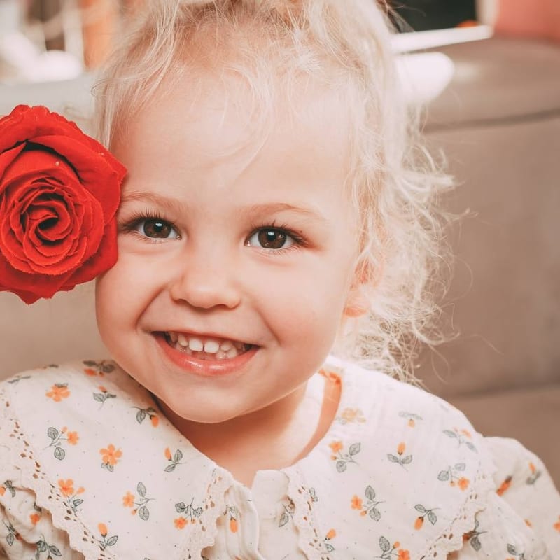 Anya beaming, holding a red rose up to her face